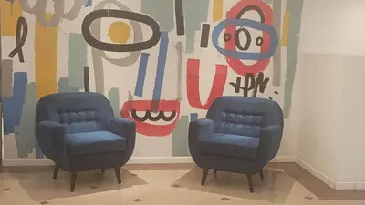 two blue chairs in front of a wall with a painting at Departamento NYC 1 - Edificio VILAUT by INMOVE Temporarios in Cordoba