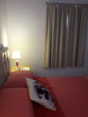 a bedroom with a bed with a red comforter and a window at Casa del Sol in Santa María