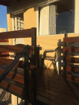 a wooden deck with a chair and a window at Depto temporario carlos paz in Villa Carlos Paz