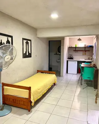 a bedroom with a yellow bed and a kitchen at Monoambiente calamuchita in Santa Rosa de Calamuchita
