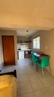 a kitchen with a table and green chairs in a room at Monoambiente calamuchita in Santa Rosa de Calamuchita