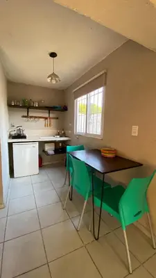 a kitchen with a table and green chairs at Monoambiente calamuchita in Santa Rosa de Calamuchita