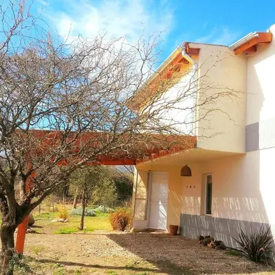 a white house with a tree in front of it at Sueño del Champaquí in Villa de Las Rosas