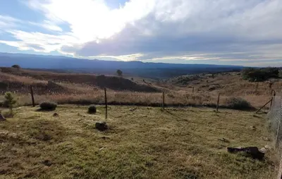 a field with a fence in the middle of a hill at Mirada al Champaqui - Departamento de Montaña in Villa Yacanto
