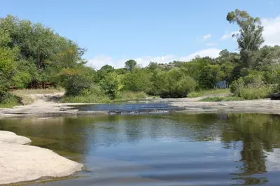 a river with rocks and trees in the background at Cabaña Las Marias 4 in Cordoba