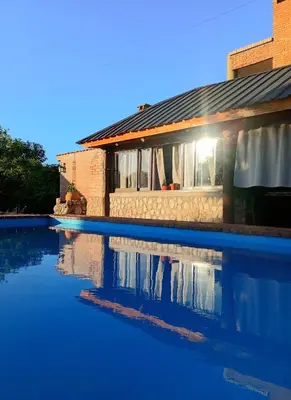 a house with a swimming pool in front of a house at Cabaña de troncos en Nono, Córdoba in Nono