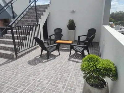 three chairs and a table on a patio with stairs at Villa Carlos Paz departamento con pileta in Villa Carlos Paz