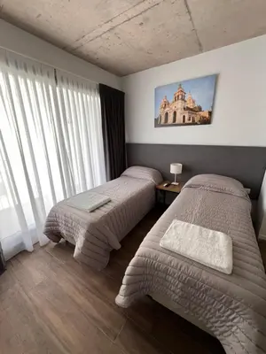 a bedroom with two beds and a large window at Departamentos en Gral Paz a pasos de clínicas in Cordoba