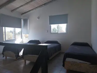 two beds in a room with two windows at Talamochita in Santa Rosa de Calamuchita