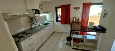 a kitchen with white cabinets and red curtains at Oasis, departamento en Carlos paz in Villa Carlos Paz