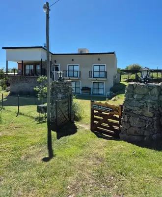 a house with a fence and a stone wall at Mirada al Champaquí - Chalet de Montaña in Villa Yacanto