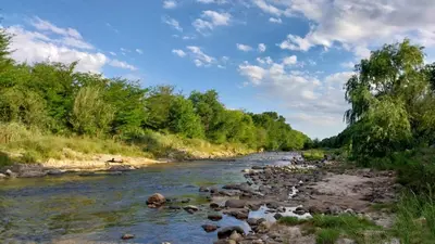 a river with rocks and trees on the side at Refugio del Rio in Los Reartes