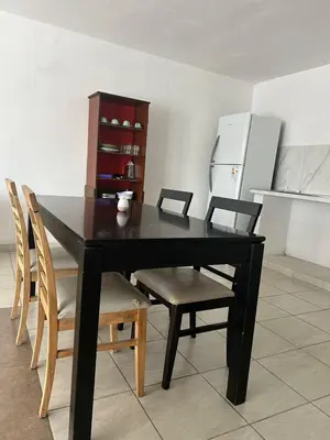 a black dining room table with chairs and a refrigerator at Depto1 in Río Cuarto