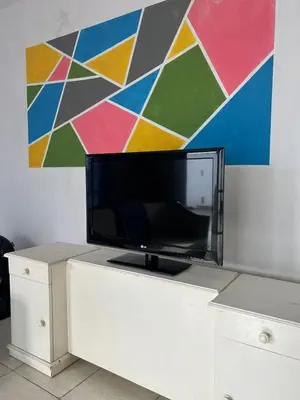 a tv on a white cabinet in front of a painting at Depto1 in Río Cuarto