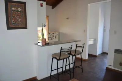 a kitchen with two bar stools and a counter at Depto Granja de Funes in Cordoba