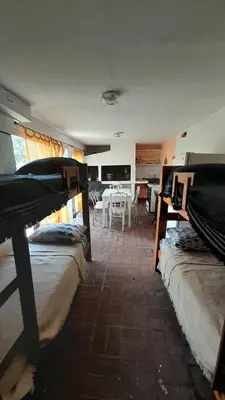 a room with three beds and a dining room with a table at Departamento Nini Villa Del Dique in Villa del Dique