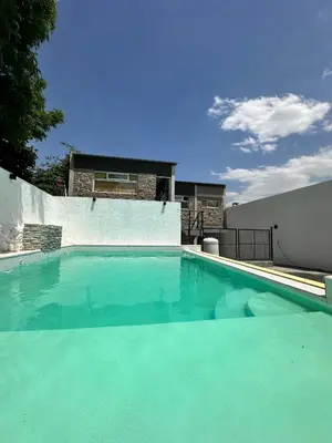 a swimming pool with blue water in front of a house at HueneyRuca in Mina Clavero