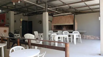 a room with white chairs and tables and a fireplace at cabañas el viejo ciprés 1 in Santa Rosa de Calamuchita