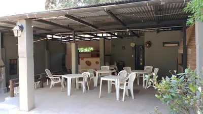 a patio with white tables and chairs under a pergola at cabañas el viejo ciprés 1 in Santa Rosa de Calamuchita