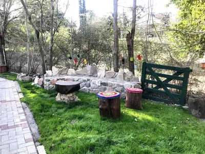 a garden with a stone wall and two stump stools at cabañas el viejo ciprés 1 in Santa Rosa de Calamuchita