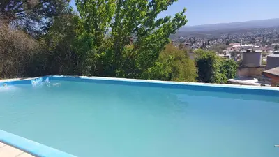 a blue swimming pool with a view of a city at Chalet de Montaña a 8 cuadras del centro de Carlos Paz con pileta de 9 x 4 in Villa Carlos Paz