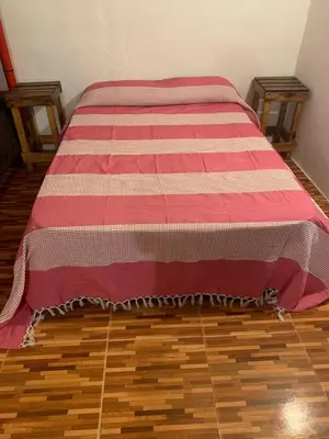 a bed with a red and white blanket on the floor at Monarcas III in Villa Carlos Paz