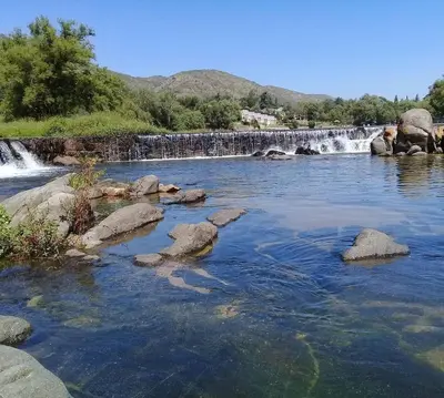 a river with rocks in front of a waterfall at Monarcas III in Villa Carlos Paz