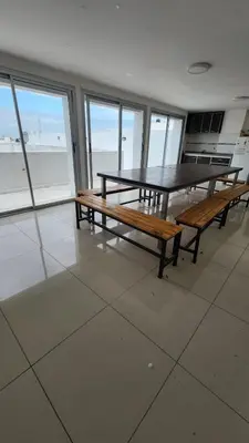 a table and benches in a room with a view of the ocean at Depto 1 dormitorio de categoria en Barrio General Paz in Cordoba