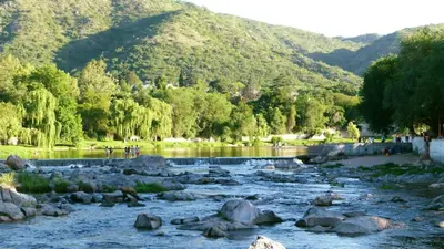 a river with rocks and mountains in the background at Habitaciones Monarcas in Villa Carlos Paz