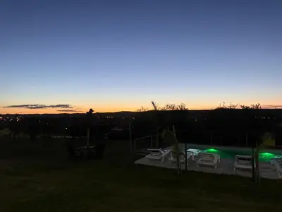 a sunset over a yard with chairs and a pool at Cabañas AdamiS in Villa Cura Brochero