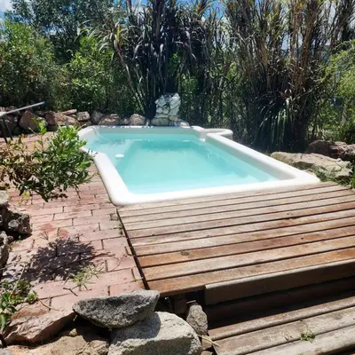 a hot tub in a garden with a wooden deck at Frente a la sierra in Quebrada de los Pozos