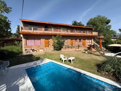 a house with a swimming pool in front of a building at Departamento frente al rio solo familias in Villa Carlos Paz