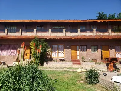 an old house with yellow doors and a yard at Departamento frente al rio solo familias in Villa Carlos Paz