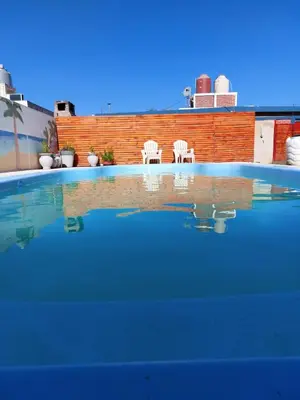 two white chairs sitting next to a swimming pool at Cabañas los materos 2 in Cordoba