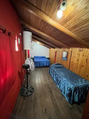 a room with two beds and a fan in a cabin at La Morada in Mina Clavero