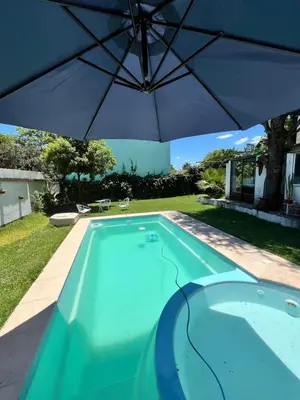 a swimming pool with an umbrella in a yard at Cabaña AGU en Cabañas María in Villa Carlos Paz