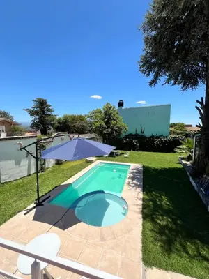 a swimming pool in a yard with an umbrella at Cabaña EMI en Cabañas María in Villa Carlos Paz