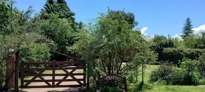 a wooden gate with a tree next to a fence at Cabaña Inti Huafi in Arroyo de Los Patos