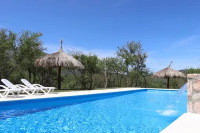 a swimming pool with two chairs and umbrellas at Refugio de las nubes in Las Rabonas