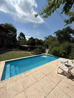 a swimming pool with two chairs and a table at Cabaña frente al balneario diquecito solo familias in Villa Carlos Paz