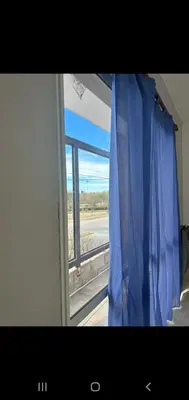 a window with a blue curtain looking out at an airport at Departamento 2 in Río Cuarto