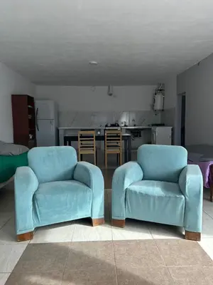 two blue chairs in a living room with a kitchen at Depto 3 in Río Cuarto