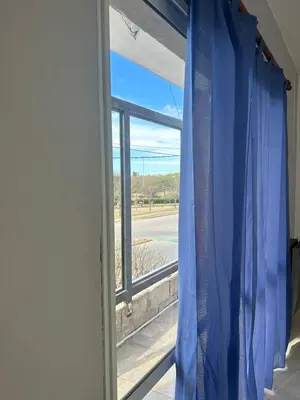 a window with a blue curtain in a room at Depto 3 in Río Cuarto