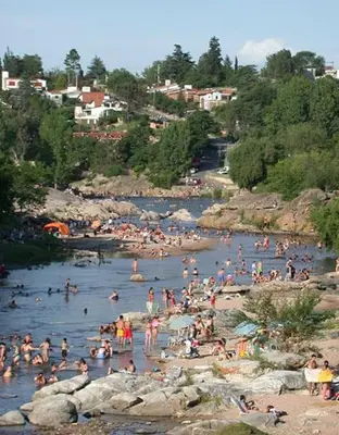 a bunch of people in the water at a beach at Departamentos Luluara in Villa Carlos Paz