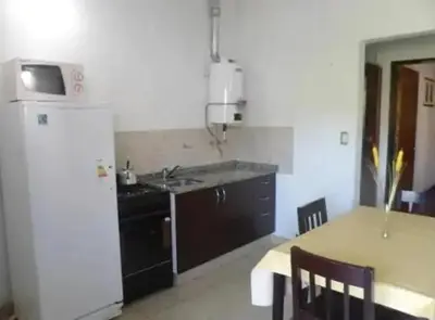 a kitchen with a sink and a refrigerator and a table at Departamentos Luluara in Villa Carlos Paz