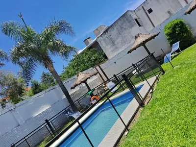 a swimming pool with umbrellas next to a building at Departamentos Luluara in Villa Carlos Paz