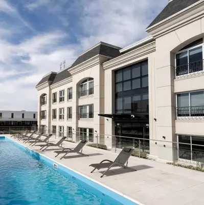 a building with a row of chairs next to a swimming pool at France Golf Apart - Flat Deluxe con estacionamiento privado, pileta y gimnasio in Río Cuarto