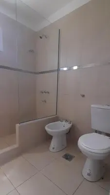 a white bathroom with a toilet and a shower at Cabañas Tinkuy II in Cortaderas