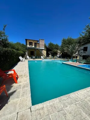 a swimming pool with a red chair next to a house at Cabañas Calimocho in Santa Rosa de Calamuchita