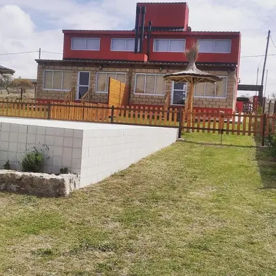 a house with a wooden fence in front of a yard at Cabañas Potrero de Garay in La Estancia